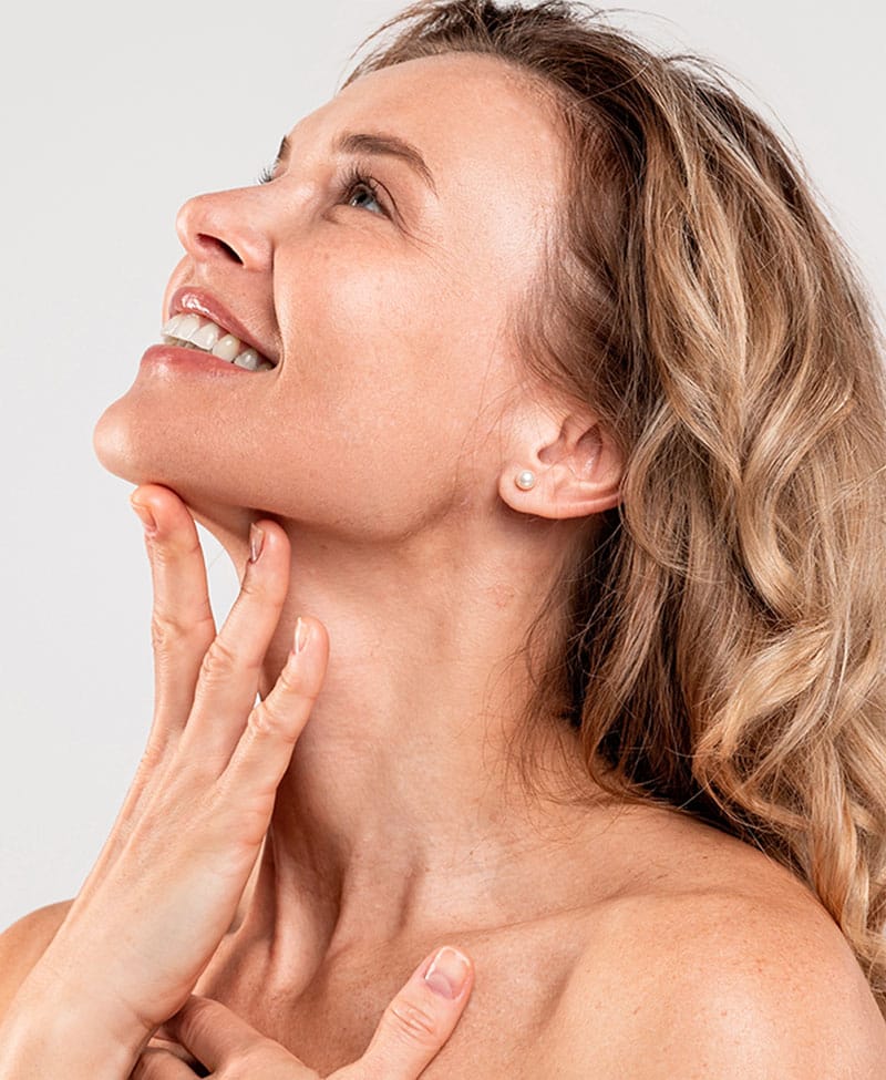 Female touching her neck on grey background